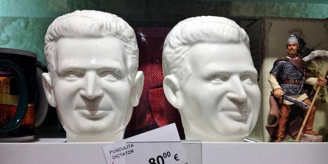 A picture taken on Dec. 7, 2014 shows a porcelain piggybank representing communist dictator Nicolae Ceausescu, next to legendary ancient and medieval kings representations on sale in the duty free shop of the Henri Coanda international airport in Otopeni, Romania. Romanians, especially those of a more senior age, have mixed feelings about the former dictator and his rule, 25 years after his execution, with many remembering predominantly the positive aspects, like the social security, of the communist times and not focusing on the extreme economic hardships and lack of basic human rights of that period, like freedom of movement or speech.(AP Photo/Vadim Ghirda)