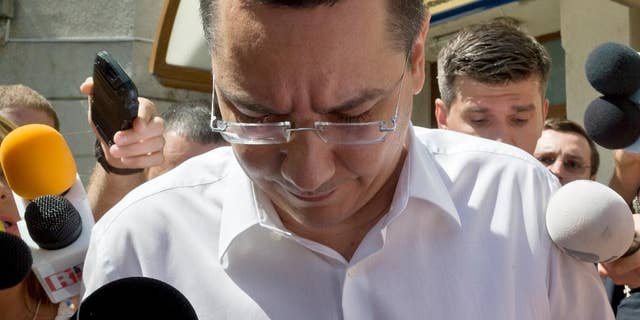 FILE - In this Monday, July 13, 2015 file photo, Romanian Premier Victor Ponta is surrounded by media as he exits the national anti-corruption prosecutors office where he was questioned in Bucharest, Romania. Romanian prosecutors on Thursday Sept. 17, 2015 formally indicted Prime Minister Victor Ponta on corruption charges, including tax evasion and money-laundering, and said he will be tried by the country’s top court. (AP Photo/Vadim Ghirda, File)
