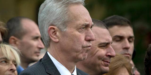 FILE - In this Oct. 8, 2015 photo from files, U.S. Ambassador Hans Klemm, center, attends a Holocaust memorial service in Bucharest, Romania. The United States’ ambassador to Romania speaking Tuesday, Oct. 13, 2015, at a conference organized by the American Chamber of Commerce, has urged politicians to continue reforms and stop political meddling in state-owned companies. (AP Photo/Vadim Ghirda, File)