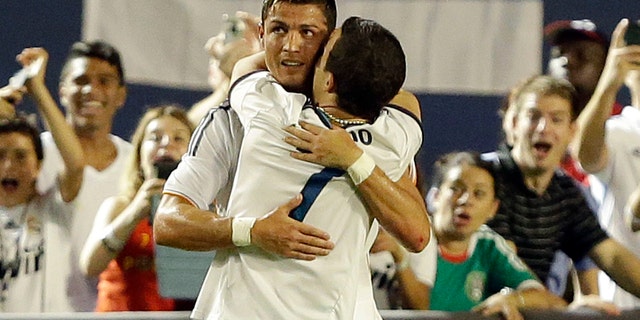 A man who ran onto the pitch hugs Real Madrid forward Cristiano Ronaldo, rear, during the second half of the International Champions Cup final soccer game between Real Madrid and Chelsea, Wednesday, Aug. 7, 2013, in Miami Gardens, Fla. (AP Photo/Wilfredo Lee)