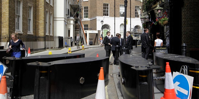 April 27, 2011: People mingle outside a pub on a street blocked off by security barriers near the Westminster Abbey in London in readiness for the royal wedding.