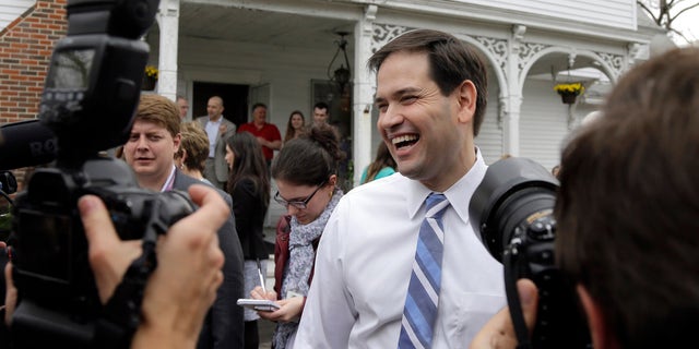 In this April 17, 2015 photo, Republican presidential candidate, Sen. Marco Rubio, R-Fla., laughs as he is surrounded by media at a campaign house party in Manchester, N.H. Devoted political allies for more than a decade, the alliance between former Florida Gov. Jeb Bush and Rubio is beginning to splinter as the one-time mentor and his political protÃ©gÃ© face off in the race for the Republican presidential nomination. (AP Photo/Elise Amendola)