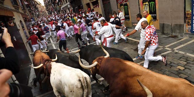 Revelers run in front of Jandilla's fighting bulls at the San Fermin Festival, in Pamplona, Monday, July 11, 2016.