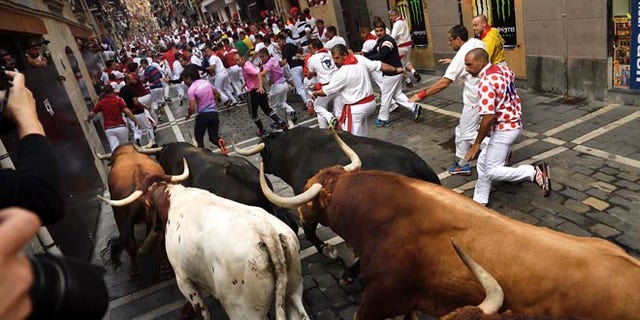 Revelers run in front of Jandilla's fighting bulls at the San Fermin Festival, in Pamplona, Monday, July 11, 2016.