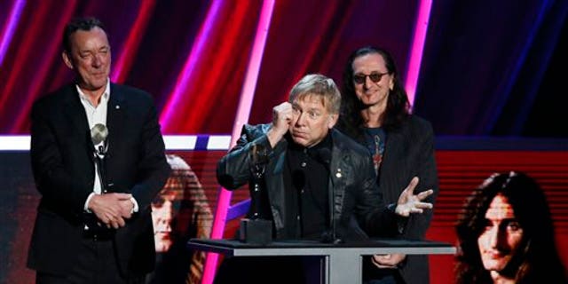 Alex Lifeson, center, Neil Peart, left, and Geddy Lee, right, of Rush accept their band's induction into the Rock and Roll Hall of Fame during the Rock and Roll Hall of Fame Induction Ceremony at the Nokia Theatre on Thursday, April 18, 2013 in Los Angeles.