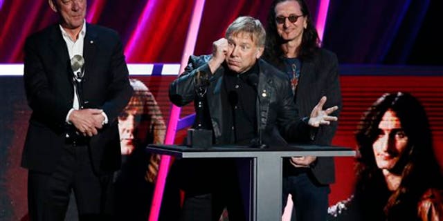 Alex Lifeson, center, Neil Peart, left, and Geddy Lee, right, of Rush accept their band's induction into the Rock and Roll Hall of Fame during the Rock and Roll Hall of Fame Induction Ceremony at the Nokia Theatre on Thursday, April 18, 2013 in Los Angeles.