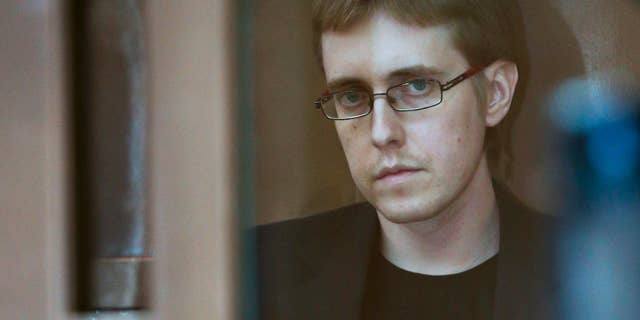 Ilya Goryachev looks from a defendants' cage in a courtroom in Moscow, Russia, Friday, July 24, 2015. Moscow’s highest court on Friday sentenced Ilya Goryachev, a leader of a militant neo-Nazi group, to life in prison after he was convicted of ordering five brutal killings including that of a prominent human rights lawyer. (AP Photo)