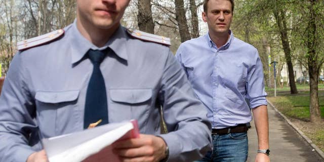 Russian opposition activist and anti-corruption crusader Alexei Navalny, right, is escorted to a court by a policeman, left, from his home, where he is currently staying under house arrest in Moscow, Russia, Tuesday, April 22, 2014. Russian opposition leader and anti-corruption crusader Alexei Navalny was found guilty in a libel case and fined US$8,400 in a court ruling that left the door open for his subsequent jailing. (AP Photo/Pavel Golovkin)