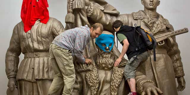 Aug. 17, 2012: Pussy Riot punk group supporters place masks on a monument to WWII heroes to resemble Pussy Riot members, at an underground station in Moscow.