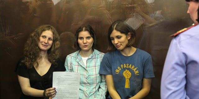 Aug. 17, 2012: Feminist punk group Pussy Riot members, from left, Maria Alekhina, Yekaterina Samutsevich, and Nadezhda Tolokonnikova show the court's verdict as they sit in a glass cage at a court room in Moscow, Russia.