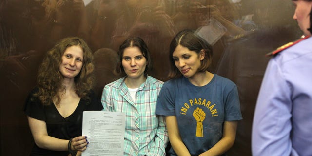 Aug. 17, 2012: Feminist punk group Pussy Riot members, from left, Maria Alekhina, Yekaterina Samutsevich, and Nadezhda Tolokonnikova show the court's verdict as they sit in a glass cage at a court room in Moscow, Russia.