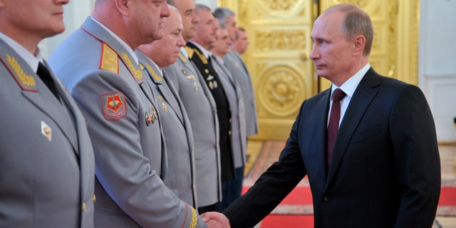 Russian President Vladimir Putin, right, shakes hands at the presentation ceremony of the top military brass in the Kremlin in Moscow, Friday, June 7, 2013. (AP Photo/RIA-Novosti, Alexei Nikolsky, Presidential Press Service)