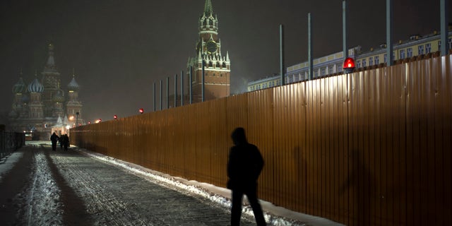 People walk past a fence around the Lenin Mausoleum in Red Square, with St. Basil Cathedral partially seen at left, in Moscow, Russia, early Thursday, Nov. 29, 2012. (AP Photo/Alexander Zemlianichenko)