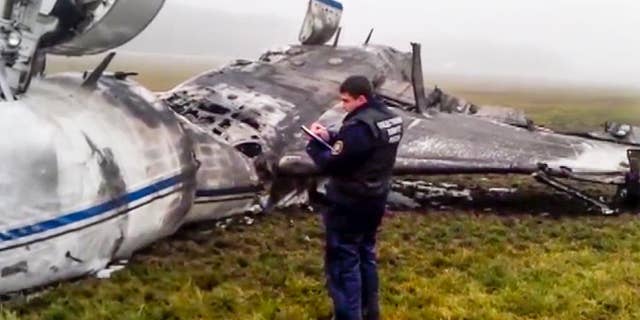 In this image made from video provided by Russian State Television Rossiya, an investigator works at the wreckage of a private jet which collided with a snowplow at Vnukovo airport in Moscow, Tuesday, Oct. 21, 2014. The head of French oil giant Total SA and three French crew members were killed at Vnukovo airport when a corporate jet, the French-made Dassault Falcon 50, collided with a snowplow, Russian investigators said Tuesday. (AP Photo) TV OUT