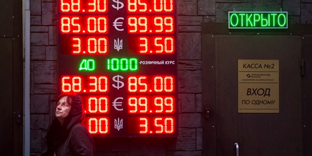Dec. 16, 2014: People wait to exchange currency near a sign advertising currency exchange rates at an exchange office in Moscow, Russia.