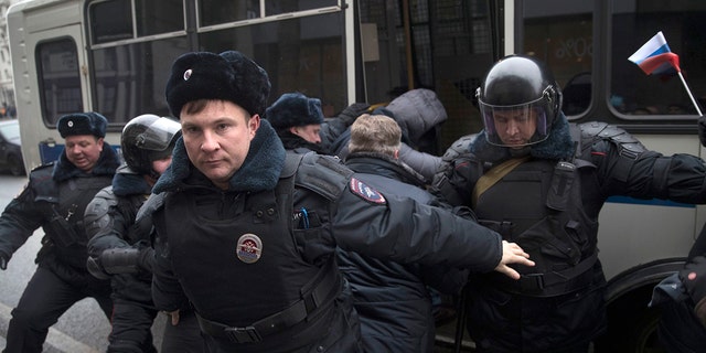 Russian opposition leader Alexei Navalny, in the background, is detained by police officers in Moscow, Russia, Sunday.