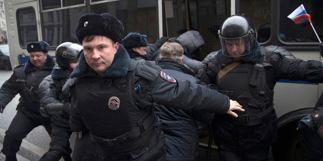 Russian opposition leader Alexei Navalny, in the background, is detained by police officers in Moscow, Russia, Sunday.