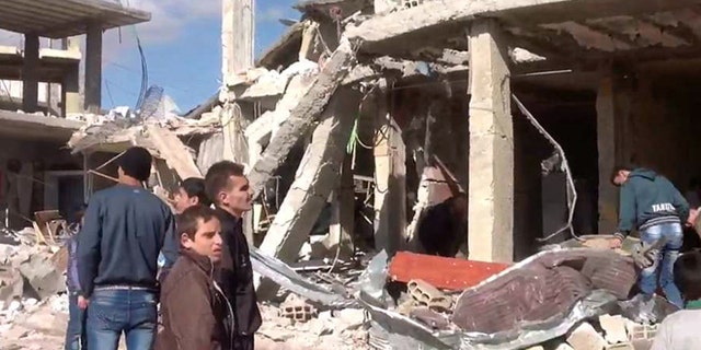 Dec. 13, 2012: In this photo released by the Syrian official news agency SANA, Syrian citizens gather in front of a damaged building destroyed by a car bomb in Qatana, 15 miles southwest of Damascus, Syria.