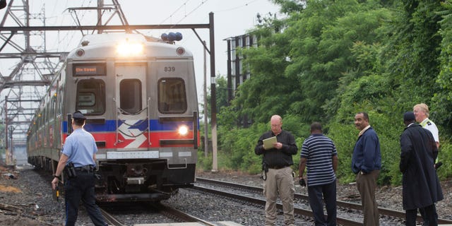 June 9, 2014: Officials stand near an idle Southeastern Pennsylvania Transportation Authority train.