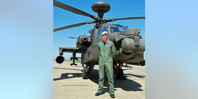 Photo released Friday July 5, 2013 shows Britain's Prince Harry posing in front of an Apache helicopter in an undisclosed location. Prince Harry has this week qualified as an Apache Aircraft Commander, the culmination of his training over the last three years.