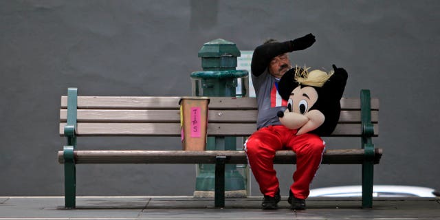 A street performer dressed as Mickey Mouse rests on a bench in Old San Juan, Puerto Rico, on July 1, 2015.