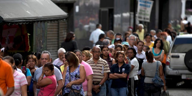 Shoppers wait in line outside of a supermarket on March 2, 2014 in Caracas, Venezuela.