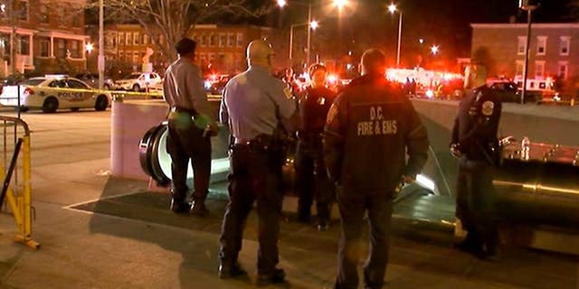 In this still image taken from video, police and fire officials stand outside the entrance to the Potomac Avenue Metro Station, Thursday night, March 12, 2015 in Washington. Transit police in Washington, D.C. fatally shot a man after responding to a call about an "unauthorized person" on the tracks in a subway tunnel. (AP Photo/WJLA-TV)