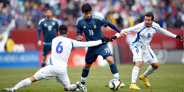 Argentina's Ever Banega battles for the ball against El Salvador's Richard Menjivar and Rafael Burgos, March 28, 2015.