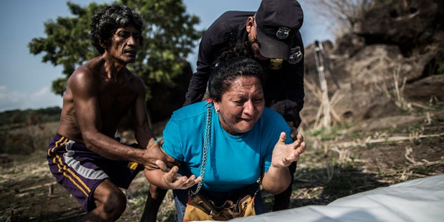 FILE - In this May 28, 2015, file photo, the sister of Alberto Hernández Escalante mourns over the body of her brother, found in a clandestine grave, in a rural area near Caserio el Chumpe, El Salvador. (AP Photo/Manu Brabo, File)