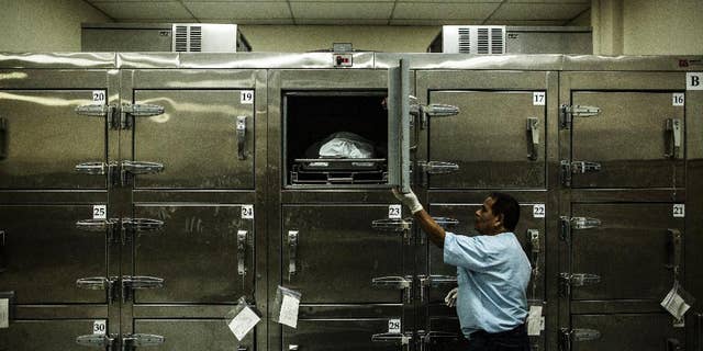 FILE - In this May 26, 2015 file photo, a forensic worker closes a morgue refrigerator door after placing a suspected gang member's body inside at the Institute of Legal Medicine in San Salvador, El Salvador. Authorities said on Wednesday, Aug. 19, 2015 that at least 125 people have been killed in the last three days as a wave of violence continues to plague the Central American nation. (AP Photo/Manu Brabo, File)