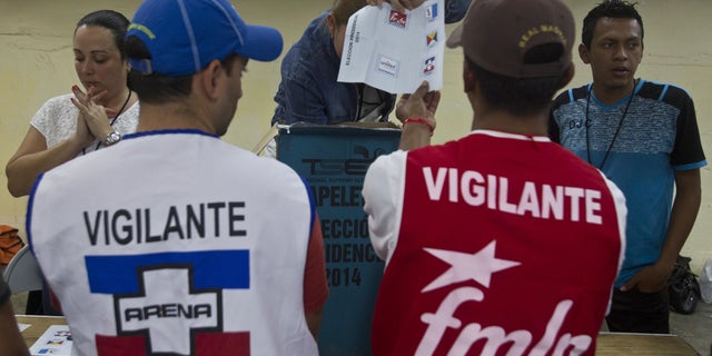 An election officer shows a ballot in front volounteers from the ruling the Farabundo Marti National Liberation Front, (FMLN) and Nationalist Republican Alliance, or ARENA, during during the vote count at a polling station in San Salvador, El Salvador, Sunday, Feb. 2, 2014. Presidential elections in two Central American countries are both referendums on political stagnation, with voters in Costa Rica deciding whether to oust the long-ruling party, and voters in El Salvador deciding whether to bring it back to power. (AP Photo/Esteban Felix)