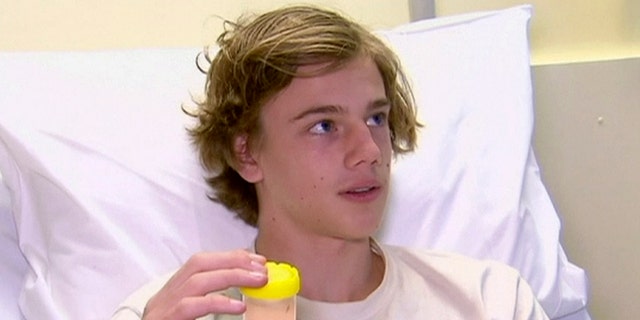 In this image made from video, Sam Kanizay, 16, holding a jar with creatures in it speaks from a bed of a hospital where he is treated, in Melbourne, Australia, Monday, Aug. 7, 2017. Kanizay walked out of the water with his feet and ankles covered in what looked like hundreds of little pin holes that were bleeding profusely. Kanizay's father, Jarrod, said hospital staff had no idea what kind of creature could have caused the injuries. (Australia Pool via AP)