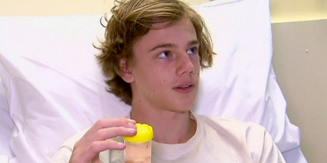 In this image made from video, Sam Kanizay, 16, holding a jar with creatures in it speaks from a bed of a hospital where he is treated, in Melbourne, Australia, Monday, Aug. 7, 2017. Kanizay walked out of the water with his feet and ankles covered in what looked like hundreds of little pin holes that were bleeding profusely. Kanizay's father, Jarrod, said hospital staff had no idea what kind of creature could have caused the injuries. (Australia Pool via AP)