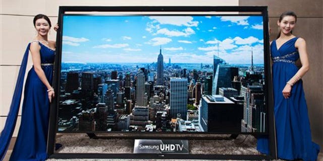 In this undated handout photo released by Samsung Electronics Co. Monday, Dec. 30, 2103, models pose with a Samsung Electronics' 110-inch UHD TV. Samsung on Monday said a 110-inch UHD TV that has four times the resolution of standard high-definition TVs is going on sales for about $150,000 in South Korea. (AP Photo/Samsung Electronics Co.)