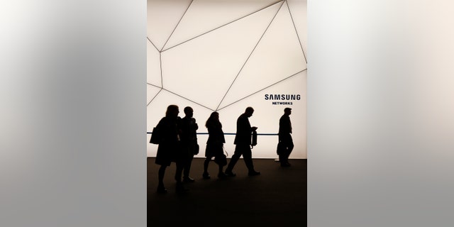 People walk past a Samsung stand while attending the Mobile World Congress in Barcelona March 2, 2015.