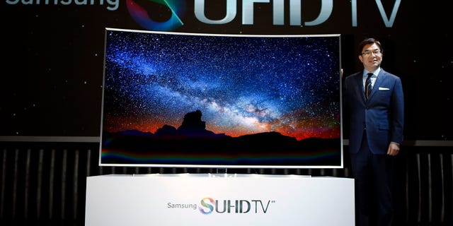 Kim Hyun-seok, head of Samsung Electronics television division, poses for photographs with a Samsung Electronics smart TV during its launch event in Seoul February 5, 2015.