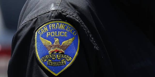 In this May 12, 2015 photo, a San Francisco Police officer stands on a street in San Francisco. The original charges were shocking enough: six San Francisco police officers were accused of stealing from suspects living in seedy residential hotels. Then federal prosecutors released racist, homophobic and ethnically insensitive email and text messages exchanged among more than a dozen officers, prompting the San Francisco district attorney to launch a wide-ranging investigation of the police department while considering dismissing up to 3,000 criminal cases involving the officers. (AP Photo/Jeff Chiu)