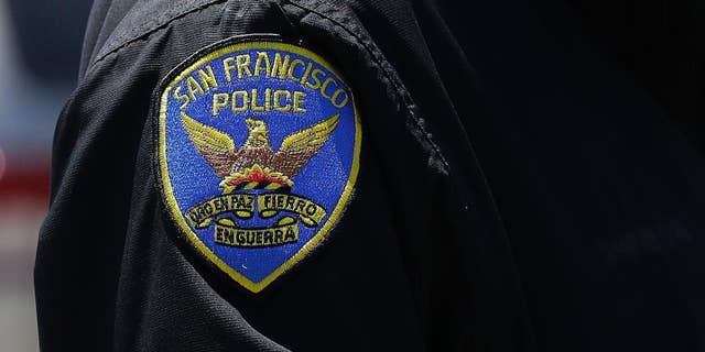 In this May 12, 2015 photo, a San Francisco Police officer stands on a street in San Francisco. The original charges were shocking enough: six San Francisco police officers were accused of stealing from suspects living in seedy residential hotels. Then federal prosecutors released racist, homophobic and ethnically insensitive email and text messages exchanged among more than a dozen officers, prompting the San Francisco district attorney to launch a wide-ranging investigation of the police department while considering dismissing up to 3,000 criminal cases involving the officers. (AP Photo/Jeff Chiu)
