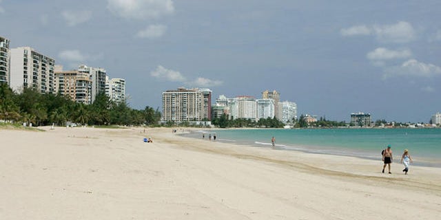** FILE **A couple of foreign tourists walk at Isla Verde Beach in San Juan, Puerto Rico in this June 11, 2007 file photo. The turquoise waters and white-sand beaches of the Caribbean appear to be losing some of their allure for U.S. tourists. Americans who flocked to the islands in record numbers until recently are finding new destinations or staying home, leading to declines of more than 10 percent this year in islands including Jamaica, St. Lucia and Grenada. (AP Photo/Andres Leighton)