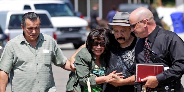 May 24: Relatives of the drowning victims walk away from the scene alongside a detective, right, in San Diego.