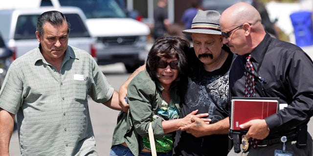 May 24: Relatives of the drowning victims walk away from the scene alongside a detective, right, in San Diego.