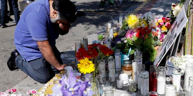 May 25, 2014: Jose Cardoso pays his respects at a makeshift memorial in front of the IV Deli Mart, where part of Friday night's mass shooting took place.