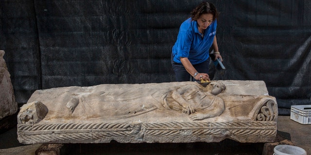 An Israeli Antiquities Authority employee cleans an 1,800 years old stone sarcophagus.
