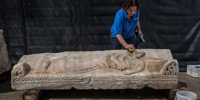 An Israeli Antiquities Authority employee cleans an 1,800 years old stone sarcophagus.