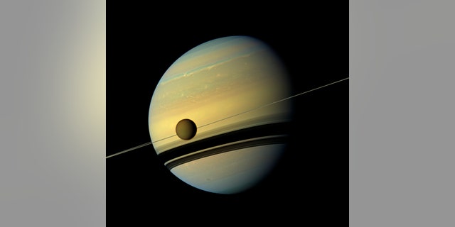 Titan, Saturn's largest moon appears before the planet as it undergoes seasonal changes in this natural color view from NASA's Cassini spacecraft in this handout released by NASA August 29, 2012.