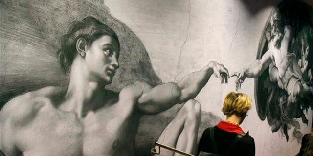 A visitors passes a poster from the Sistine Chapel showing "Creation of Adam" at the Albertina museum, in Vienna, Austria, on Wednesday, Oct. 6, 2010.