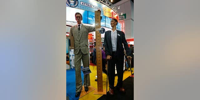 The world's tallest man, Sultan Kosen of Turkey, measuring 8 feet 3 inches, right, poses next to a figure of the tallest man in history, Robert Wadlow.