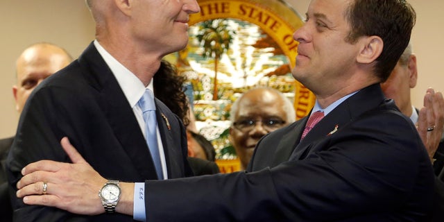 Florida Gov. Rick Scott, left, congratulates Miami-Dade Property Appraiser Carlos Lopez-Cantera after naming him lieutenant governor and his running mate for 2014, during a news conference, Tuesday, Jan. 14, 2014 in Miami. (AP Photo/Wilfredo Lee)