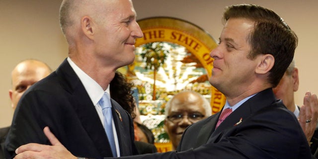 Florida Gov. Rick Scott, left, congratulates Miami-Dade Property Appraiser Carlos Lopez-Cantera after naming him lieutenant governor and his running mate for 2014, during a news conference, Tuesday, Jan. 14, 2014 in Miami. (AP Photo/Wilfredo Lee)