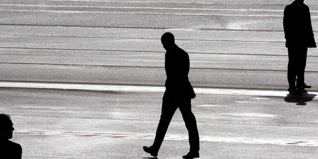 President Barack Obama, center, and two secret service agents are silhouetted as he walks towards Marine One helicopter upon arrival at Schiphol Amsterdam Airport, Netherlands, Monday March 24, 2014. Obama will attend the two-day Nuclear Security Summit in The Hague. (AP Photo/Peter Dejong, POOL)